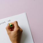 A hand using correction fluid to fix a spelling error on paper.