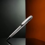 Elegant pen on reflective surface with artistic lighting, showcasing minimal design.