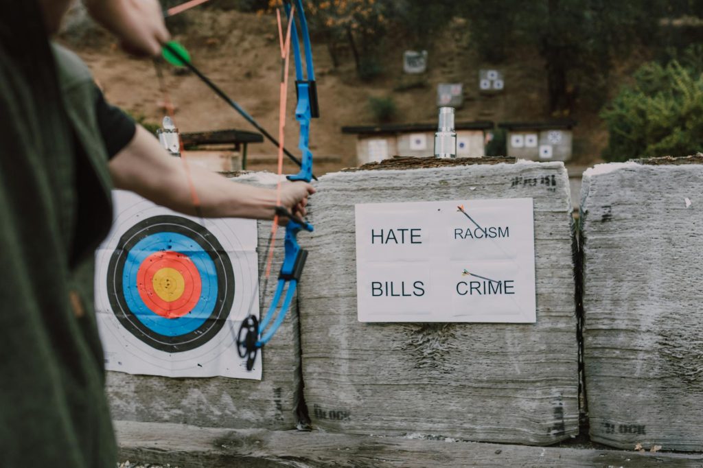 An archer aims at targets with words representing challenges outdoors, symbolizing overcoming obstacles.