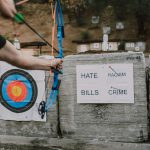 An archer aims at targets with words representing challenges outdoors, symbolizing overcoming obstacles.