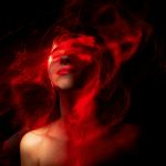 A creative abstract portrait featuring vibrant red neon effects enveloping a human face in darkness.