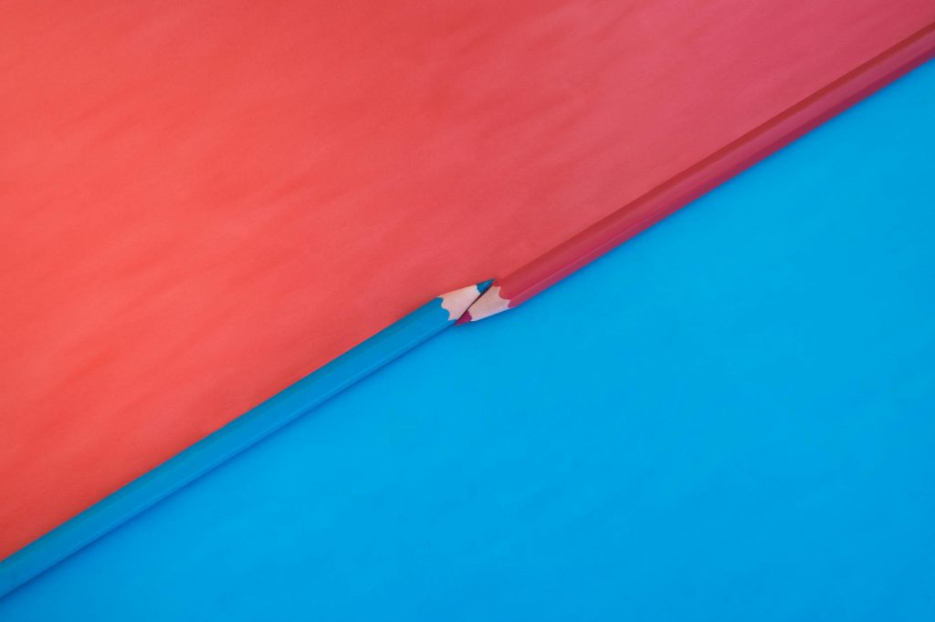 Abstract composition featuring red and blue pencils on contrasting red and blue backgrounds.
