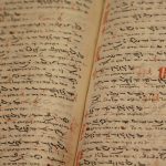 Close-up of an ancient manuscript with handwritten texts and ink inscriptions.