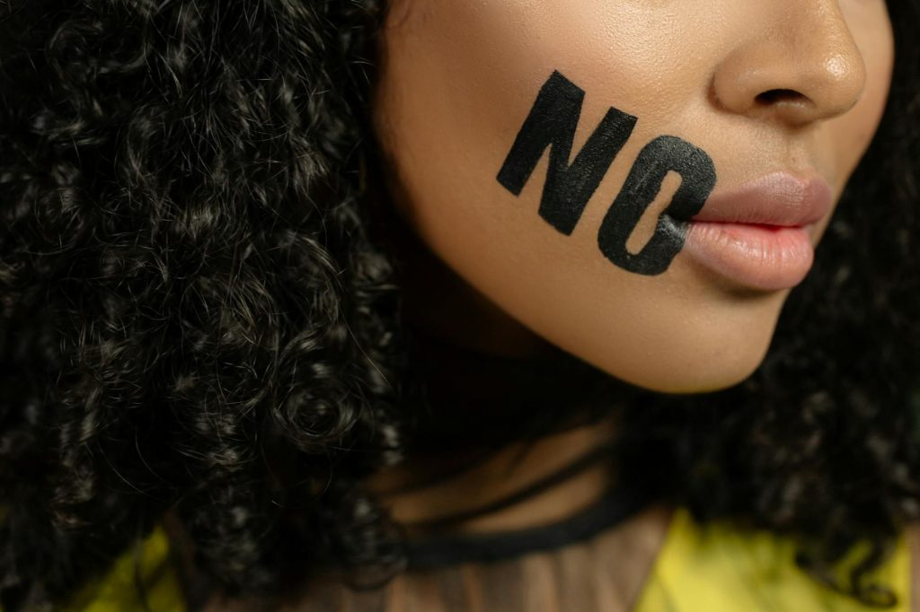 Close-up of a woman with 'No' painted on her face, conveying a powerful message.
