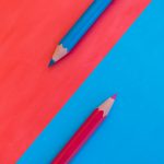 A vibrant and minimalistic composition with red and blue pencils on contrasting backgrounds.